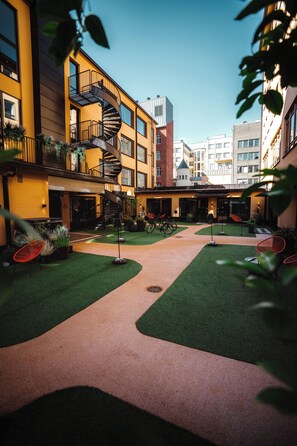 A courtyard with a spiral staircase, outdoor seating, and greenery.