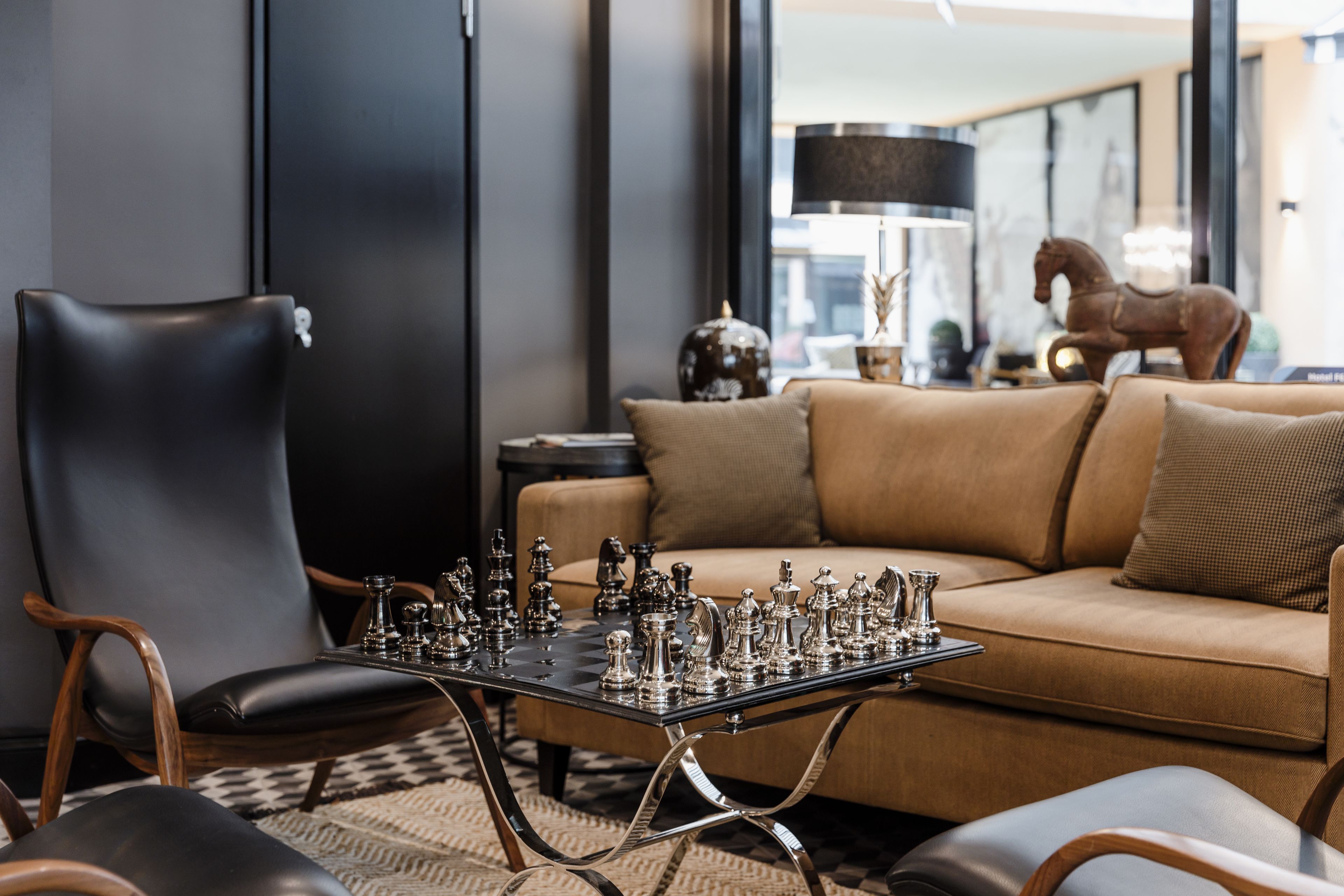 A modern living room with a chessboard, leather armchairs, a sofa, and a lamp.