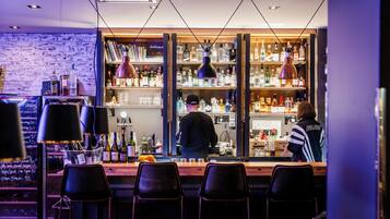 Un bar con pared de ladrillo, estantes llenos de botellas de licor y taburetes.
