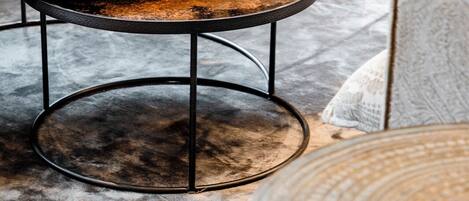 A round metal table with a worn surface, placed on a grey textured rug.