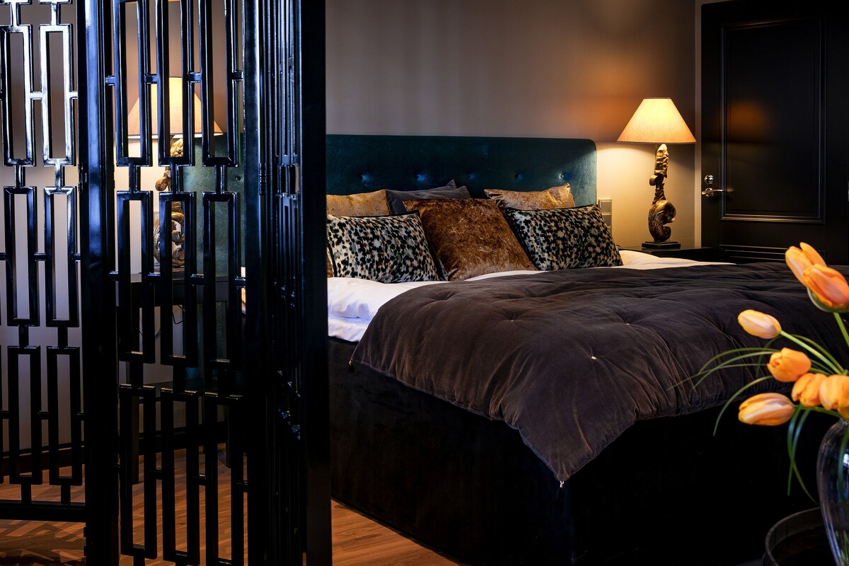 Une chambre à coucher avec un lit, des oreillers, une lampe et un mur décoratif.