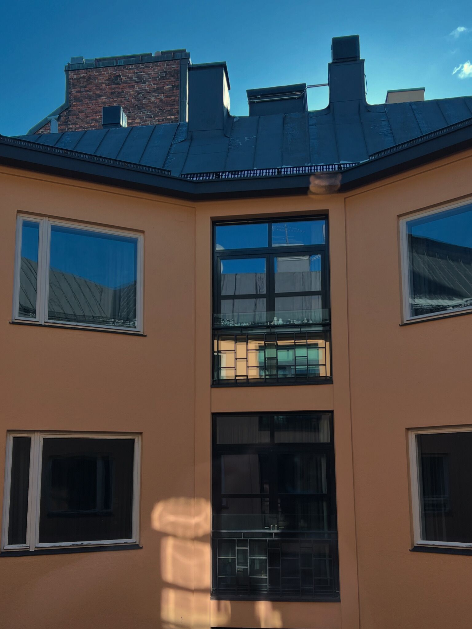 A multi-story building with a flat roof, multiple windows, and a brick chimney.