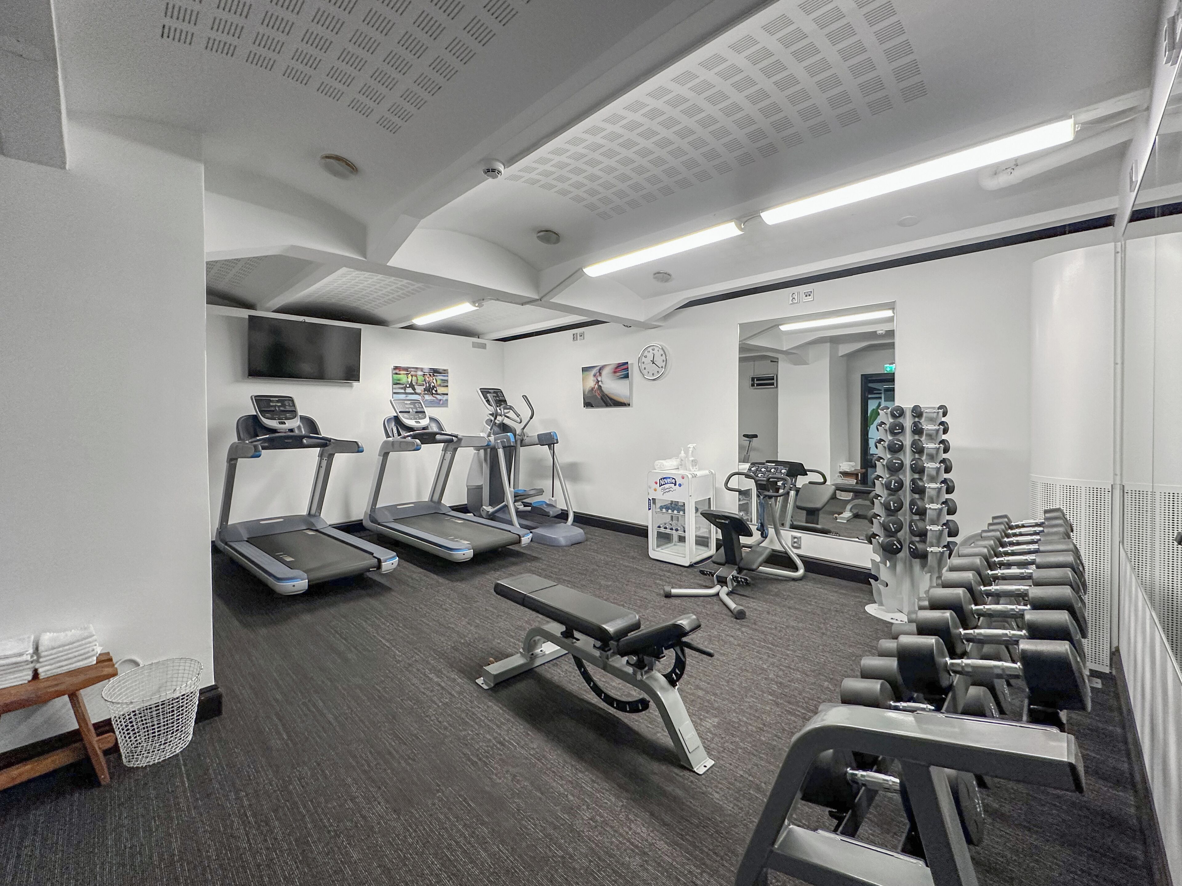 Et moderne fitnesscenter med løbebånd, styrkemaskiner og håndvægte.