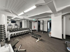 A gym with treadmills, dumbbells, and weight machines.