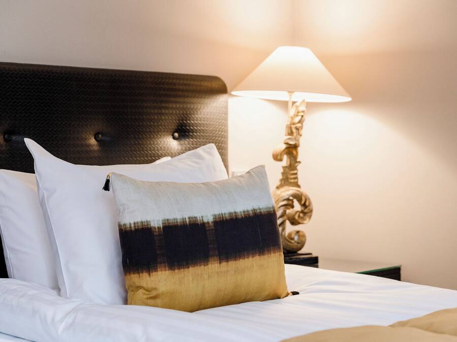 A neatly made bed with white bedding and a mix of white and multicolored pillows.