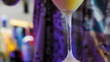 Une personne qui ajoute une garniture à un cocktail servi dans un verre à martini.