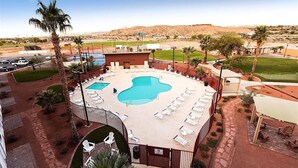 A hotel with a pool area, multiple lounge chairs, and a desert landscape in the background. - Holiday Inn Resort Mesquite by IHG (Mesquite)