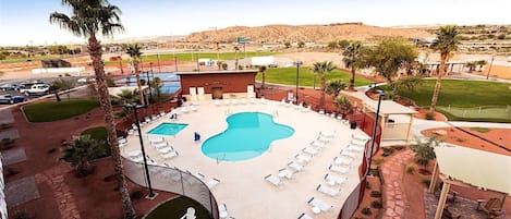 A hotel with a pool area, multiple lounge chairs, and a desert landscape in the background.