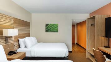 A hotel room with a bed, bedside table, lamp, and a painting on the wall.