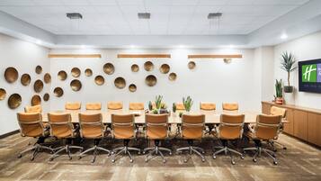 A conference room with a long table, multiple chairs, and a wall decorated with circular mirrors.