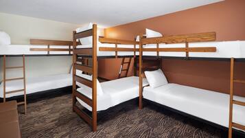A bunk bed room with a patterned carpet, wooden bunk beds, and a ladder.