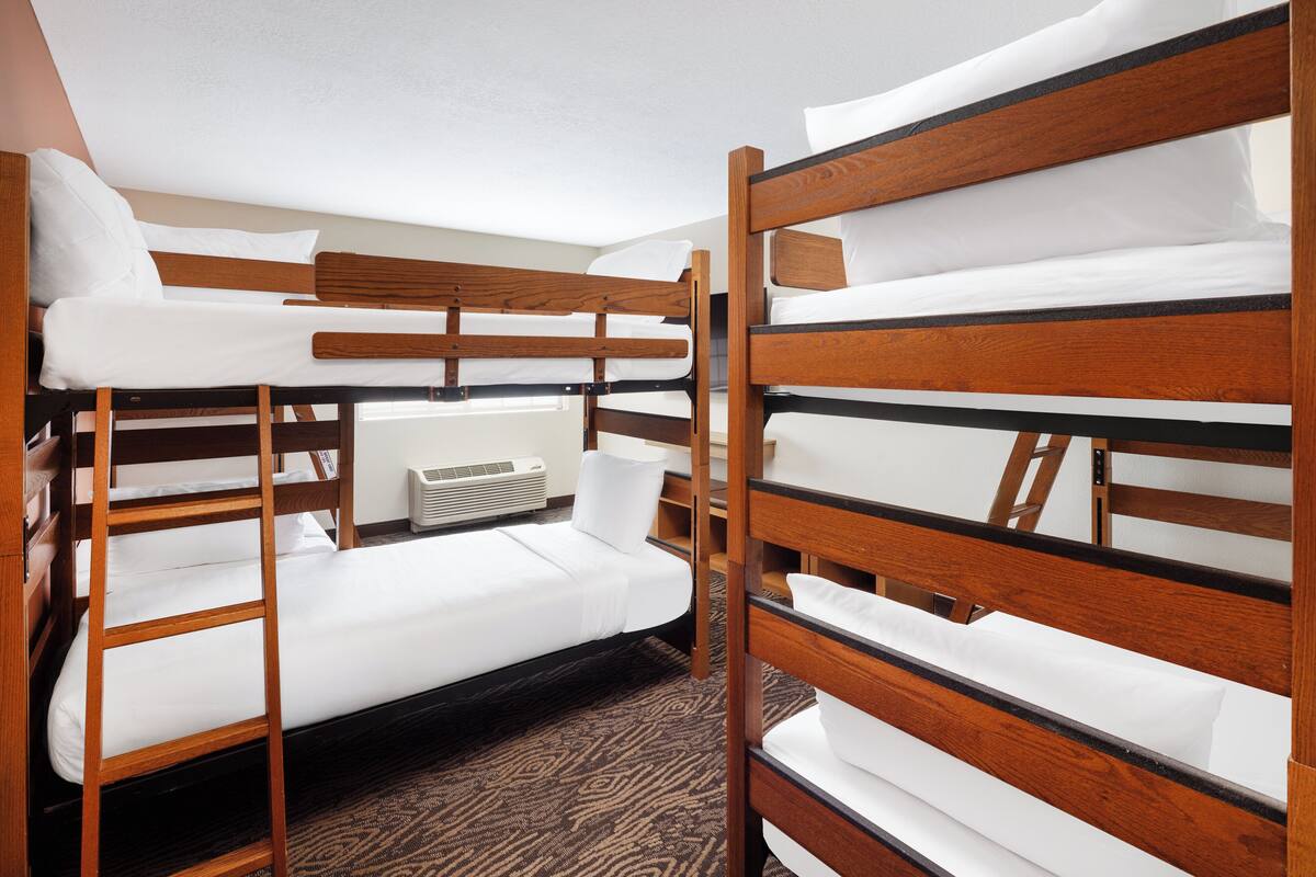 A bunk bed room with a carpeted floor and a wall-mounted heater.