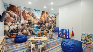 A children's playroom with a mural of a desert landscape, a play table, bean bags, and a bookshelf. - Holiday Inn Resort Mesquite by IHG (Mesquite)