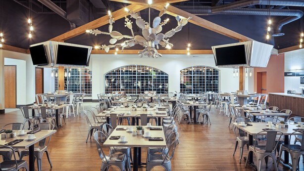 A spacious dining area with multiple tables and chairs, large windows, and a unique ceiling chandelier. - Holiday Inn Resort Mesquite by IHG (Mesquite)