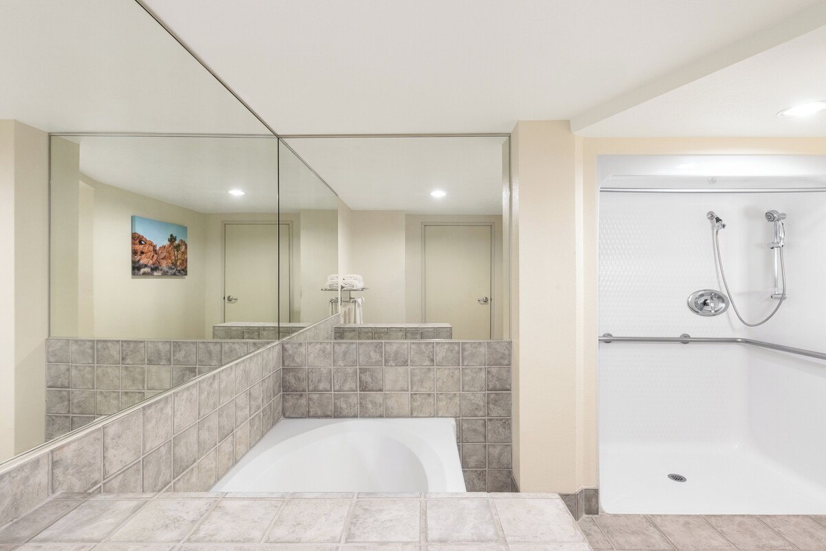 A modern bathroom with a bathtub, a shower, and a large mirror.