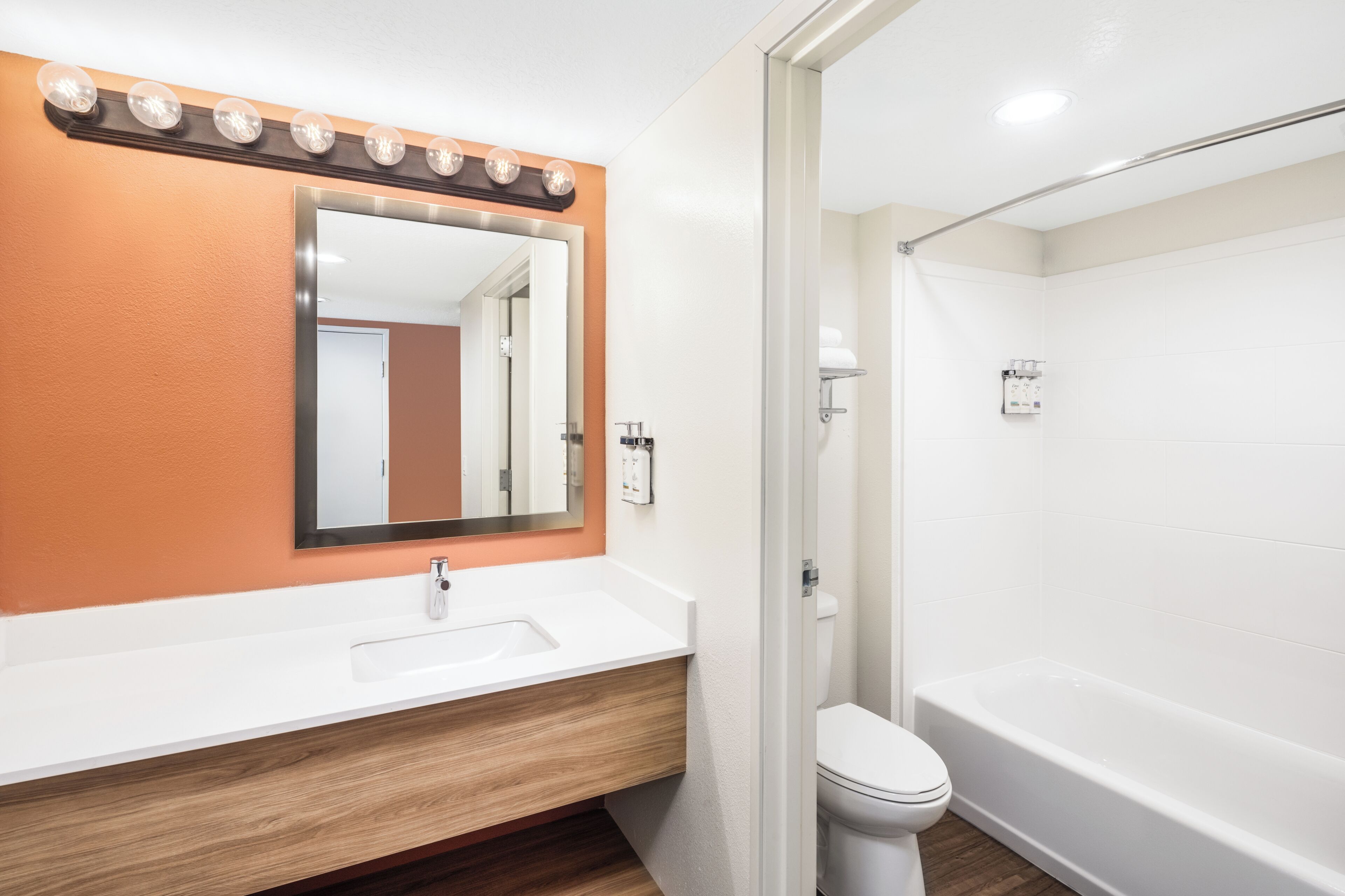 Un baño con lavamanos blanco, espejo y bañera.