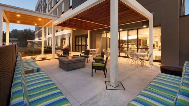 An outdoor patio area with seating, a fire pit, and a covered seating area. - Home2 Suites by Hilton Hasbrouck Heights (Hasbrouck Heights)