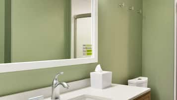 A modern bathroom with a large mirror, a sink, a toilet, and a vanity with drawers.