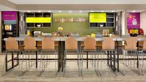 A restaurant with a long counter, multiple chairs, and a sign that reads "inspired table". - Home2 Suites by Hilton Hasbrouck Heights (Hasbrouck Heights)