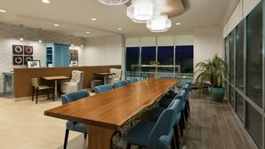 Una sala de conferencias moderna con una mesa de madera, sillas azules e iluminación colgante.
