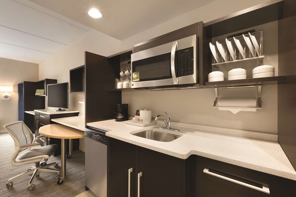 Una cocina moderna con microondas integrado, pileta de acero inoxidable y cafetera.