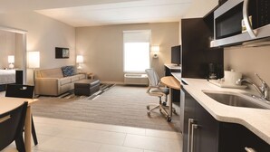 Una cocina moderna con microondas integrado, un fregadero y una zona de comedor con mesa y sillas.