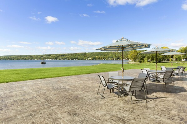 An outdoor patio with tables and chairs, overlooking a lake.