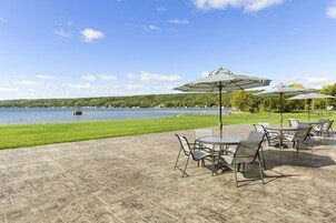 Un patio al aire libre con mesas y sillas, con vistas a un lago.