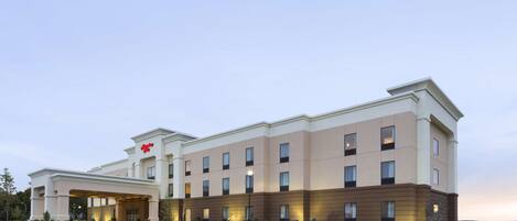 A multi-story hotel with a flat roof, a covered entrance, and a parking lot.