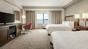A hotel room with two beds, a TV, a desk, and a chair.