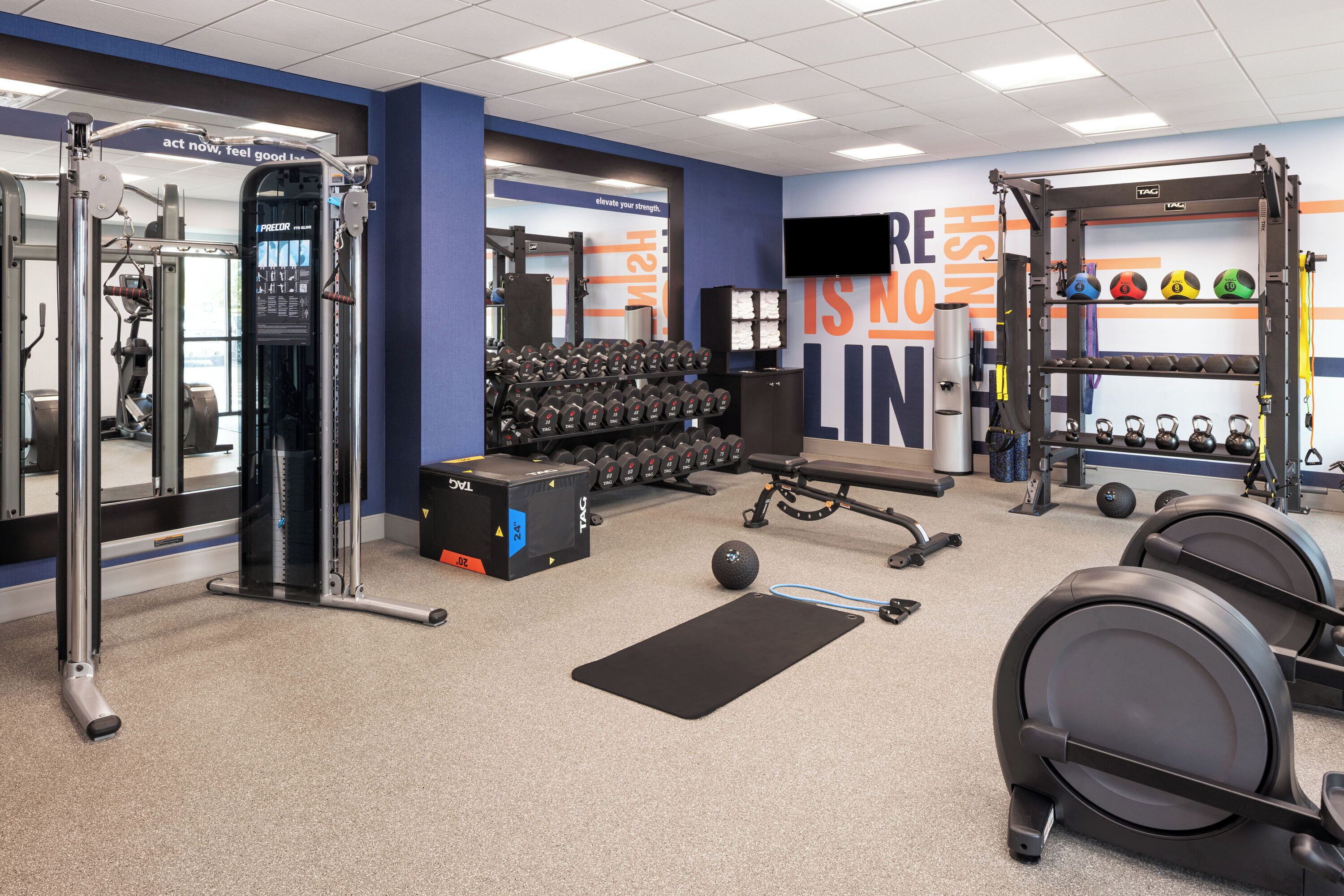 A gym with weightlifting equipment, dumbbells, and exercise mats.