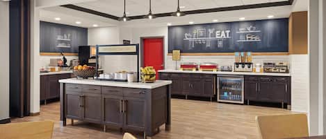 Una cocina moderna con una isla central, muebles oscuros y una barra para desayunos.