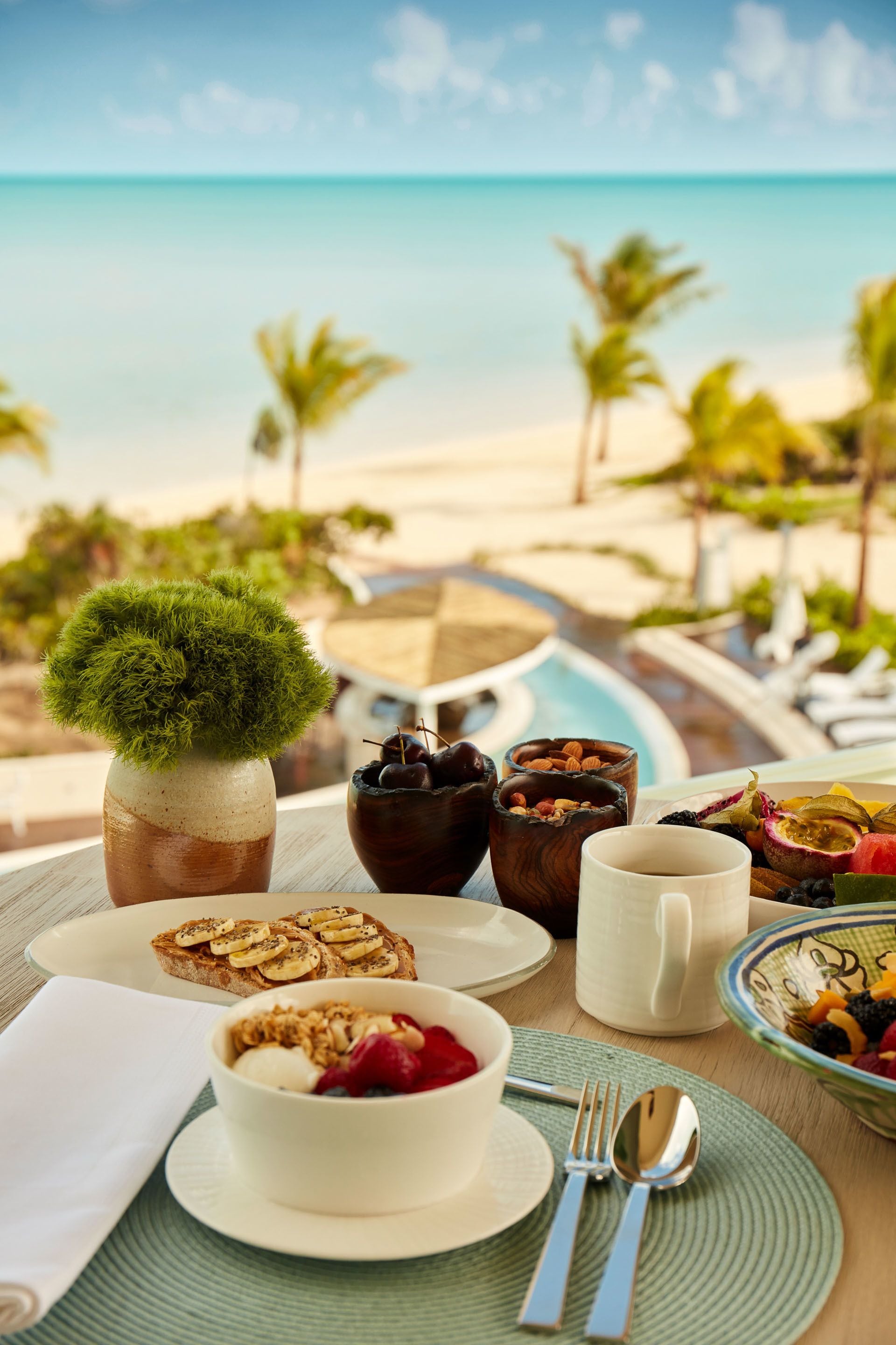 Una mesa de desayuno con vista a la playa y palmeras.