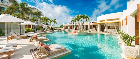 A resort pool area with sun loungers, umbrellas, and palm trees. - The Shore Club Turks and Caicos (Providenciales)