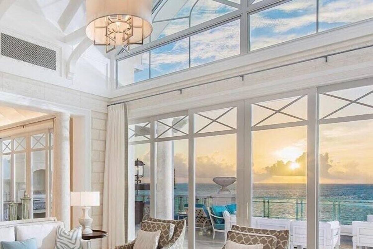 Un salón amplio con un gran ventanal con vistas al mar, amoblado con un sofá, sillas y una mesita de centro.