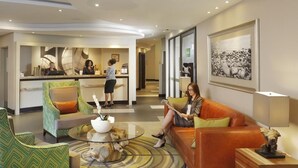 Eine Hotelhalle mit einer Rezeption, einer Sitzecke und Kunstwerken an den Wänden.