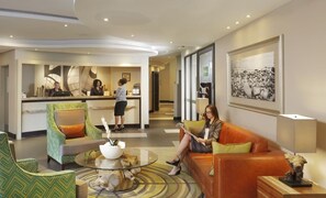 A hotel lobby with a reception desk, seating area, and a framed artwork on the wall. - Peermont Metcourt at Umfolozi (Empangeni)