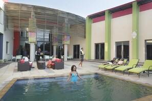 Un espace piscine avec des chaises longues et un coin salon abrité.