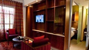 A modern living room with a flat-screen TV, red upholstered furniture, and a built-in entertainment unit.