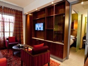 Ein modernes Wohnzimmer mit einem Flachbildfernseher, roten Polstermöbeln und einer eingebauten Unterhaltungseinheit.