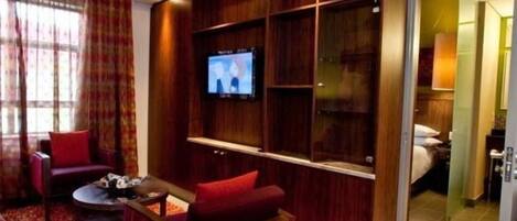 A modern living room with a TV mounted on a wooden wall, red sofas, and a coffee table.
