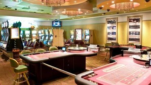 A casino with multiple slot machines, blackjack tables, and a large chandelier. - Peermont Metcourt at Umfolozi (Empangeni)