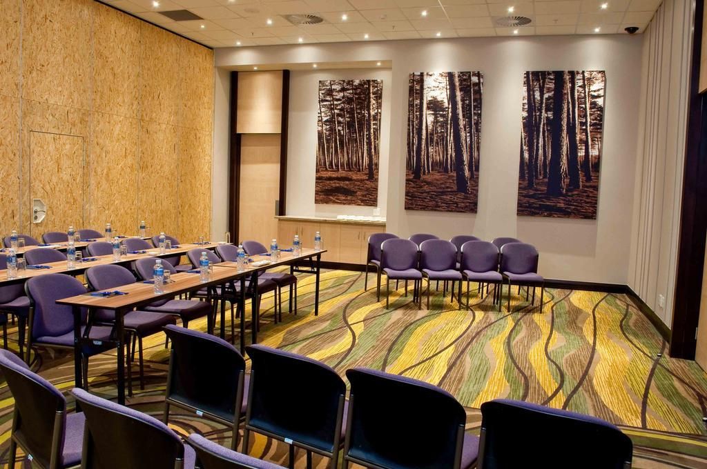 A conference room with a long table, multiple chairs, and a carpeted floor.