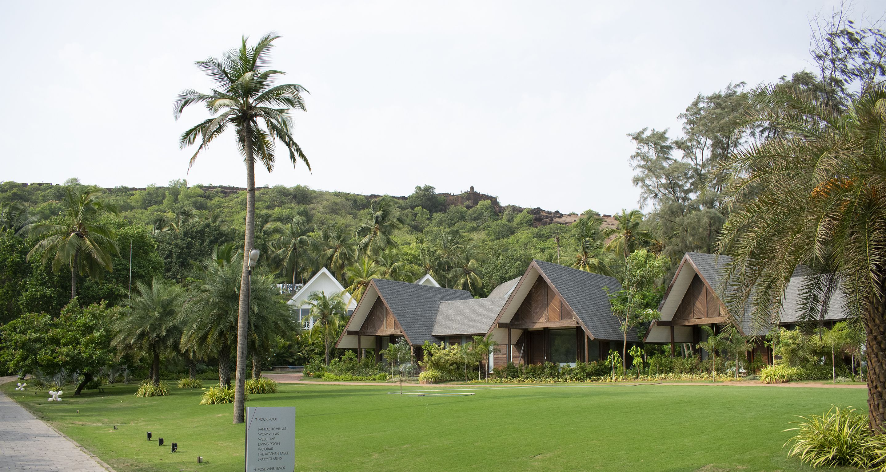 Un resort con varias construcciones tipo bungalow, un césped bien cuidado y un letrero que indica servicios como piscina y spa.