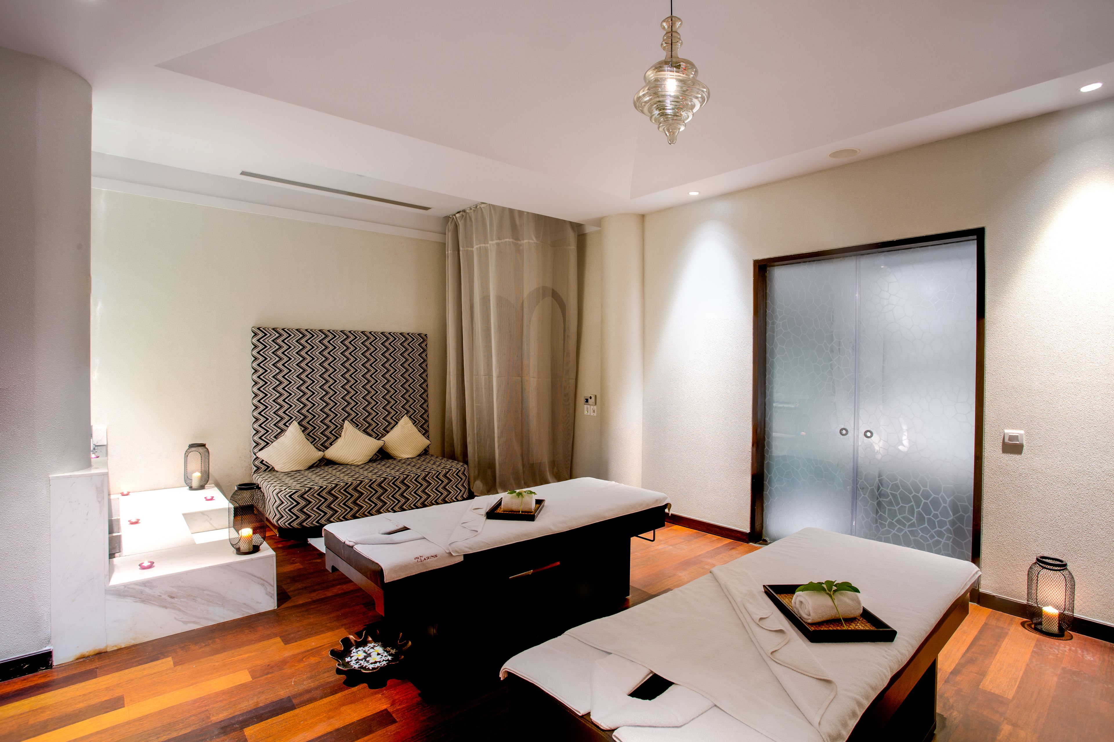 A modern room with a massage table, a sofa with patterned cushions, and a large sliding door.