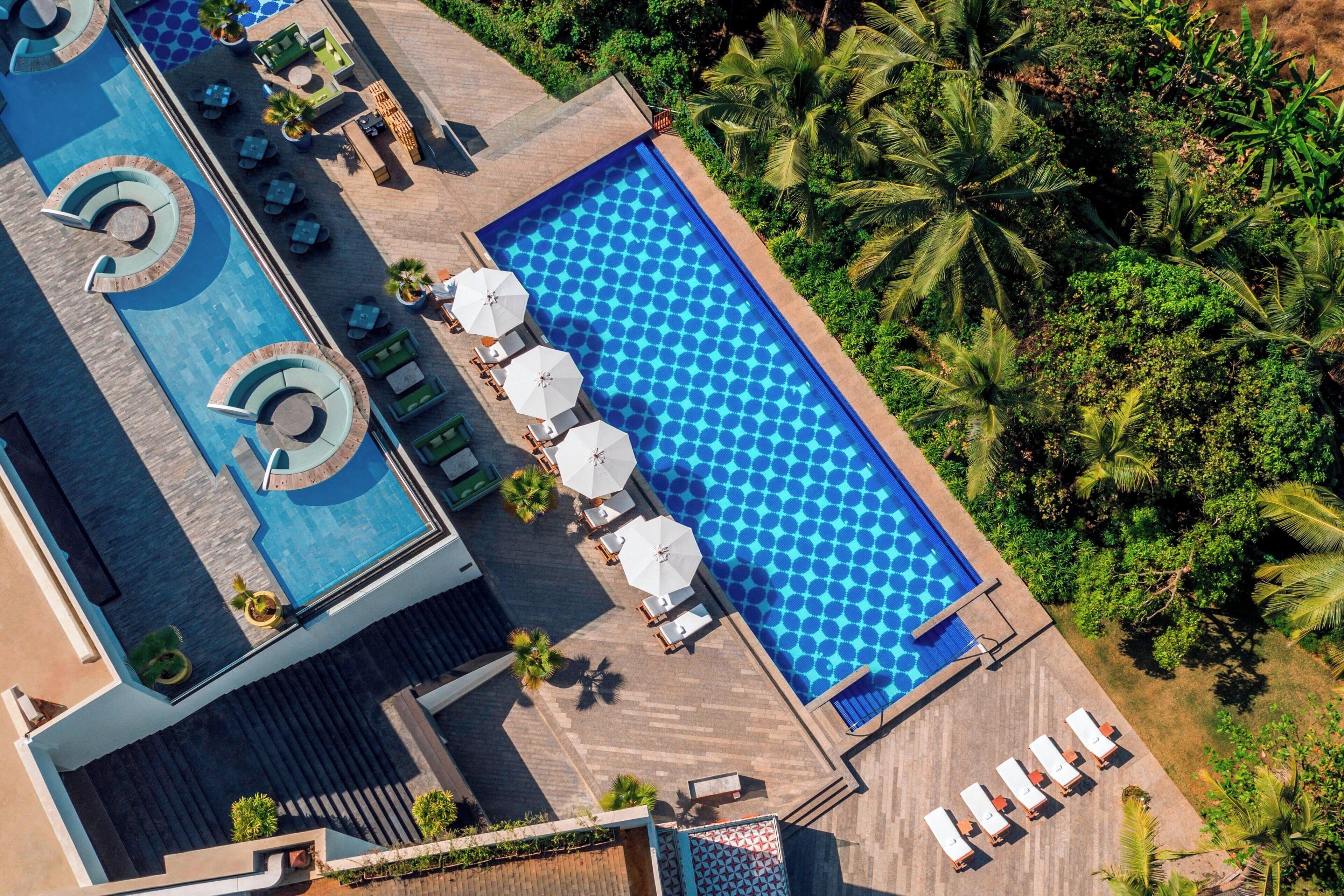 A rooftop pool with multiple sections, sun loungers, and umbrellas.