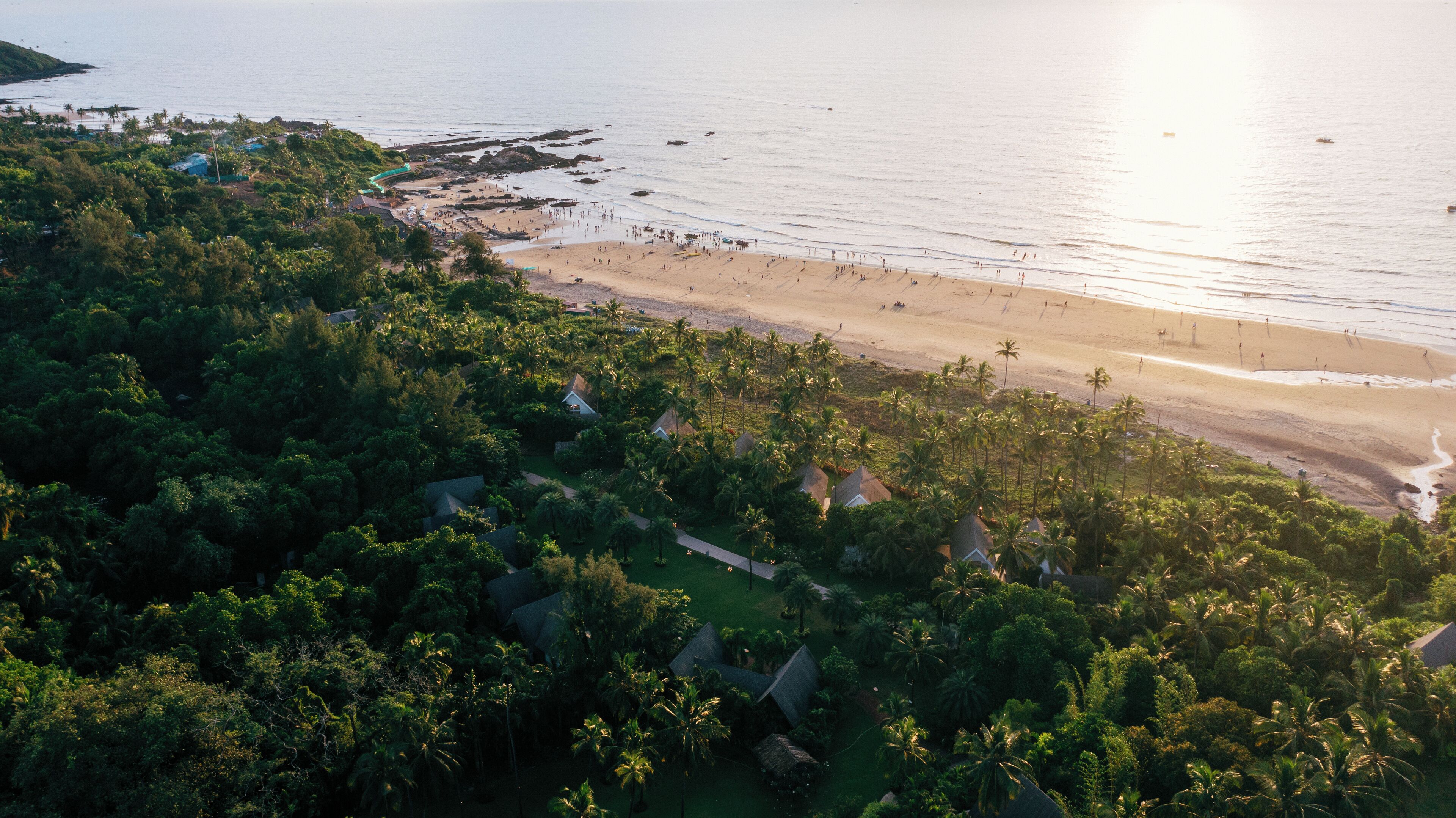 A tropical resort with dense greenery, beachfront villas, and a sandy beach.