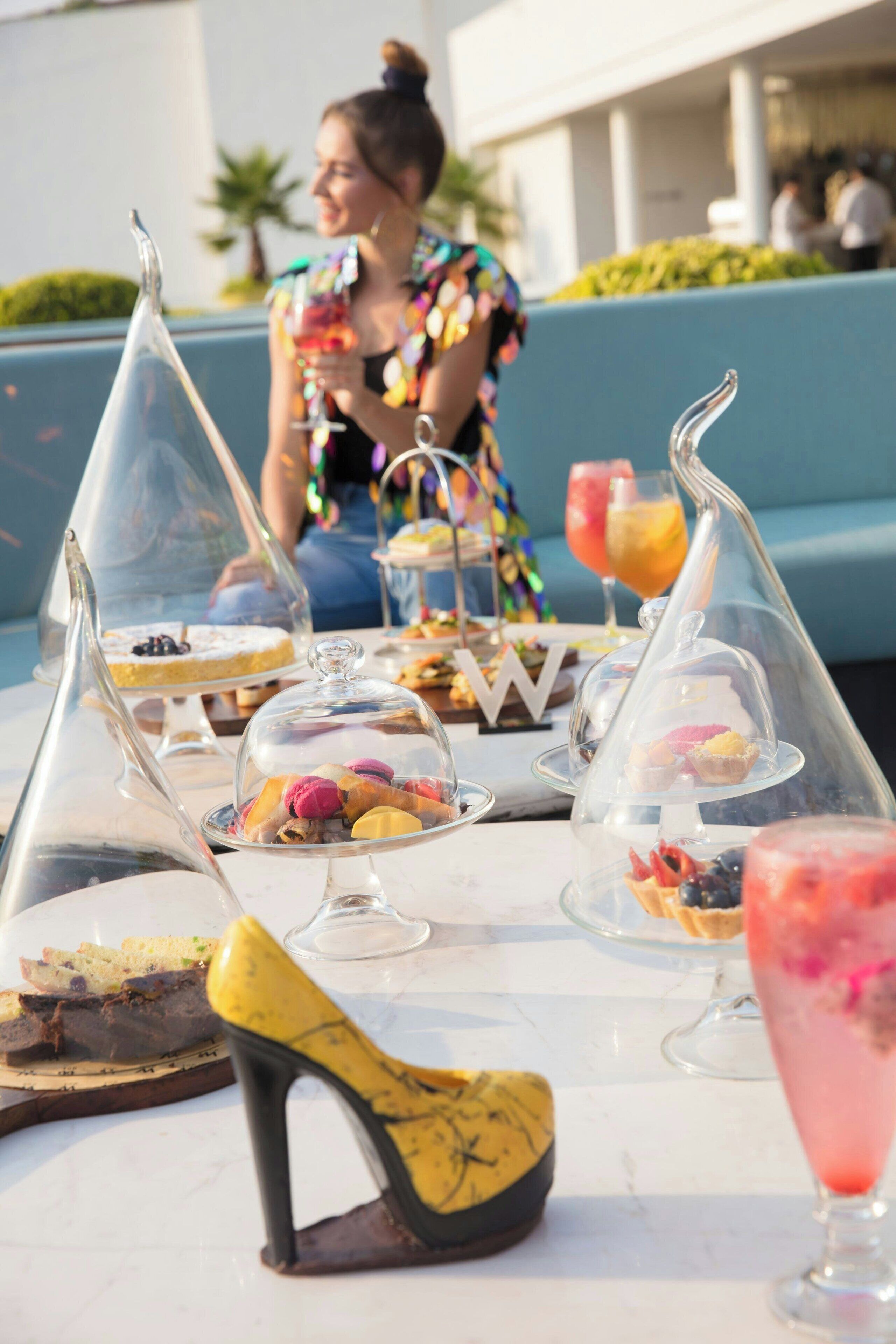 Une table avec des plats de dessert et une chaussure à talons hauts.