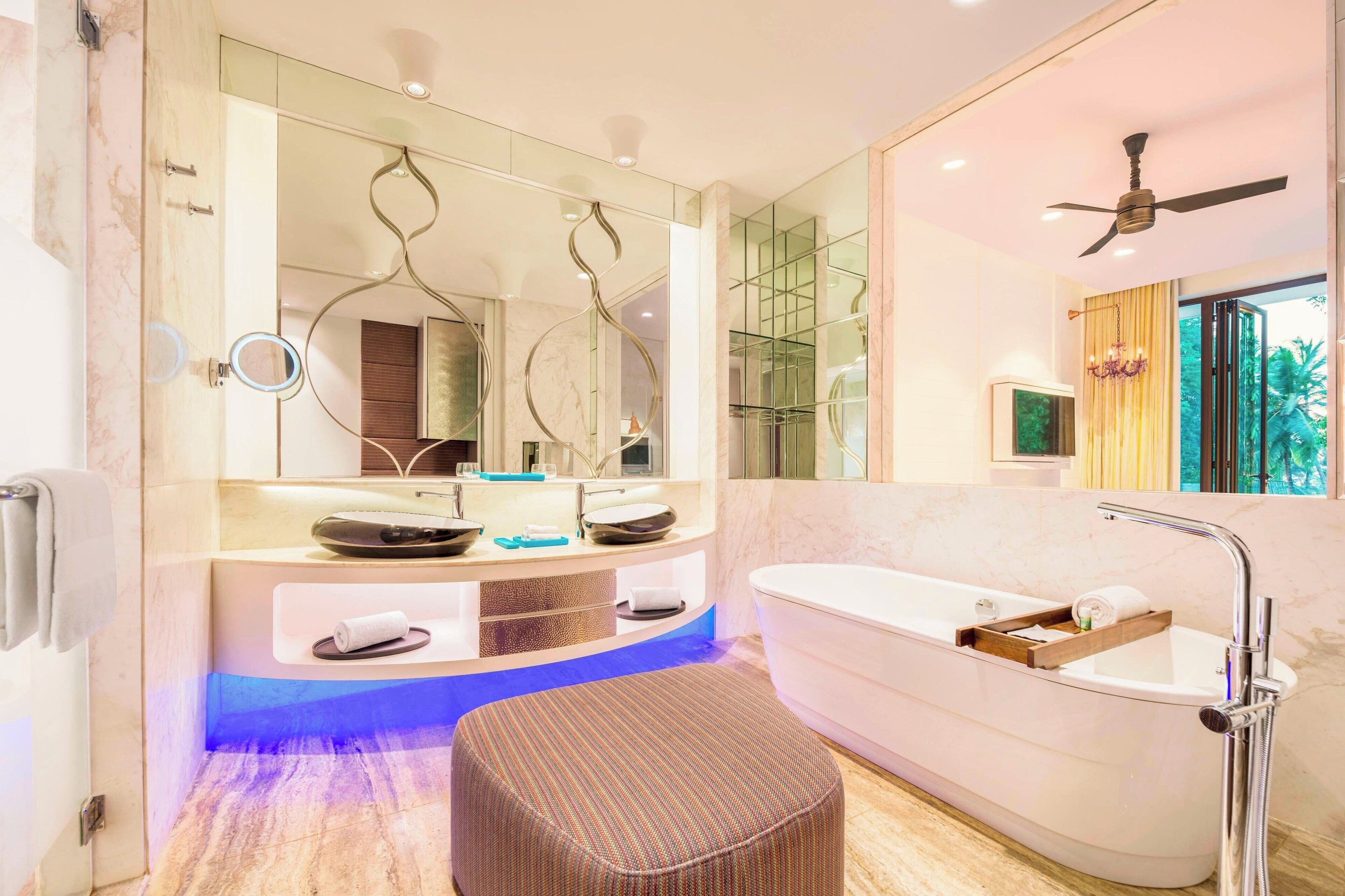 A modern bathroom with a large mirror, a bathtub, and a vanity with a sink.