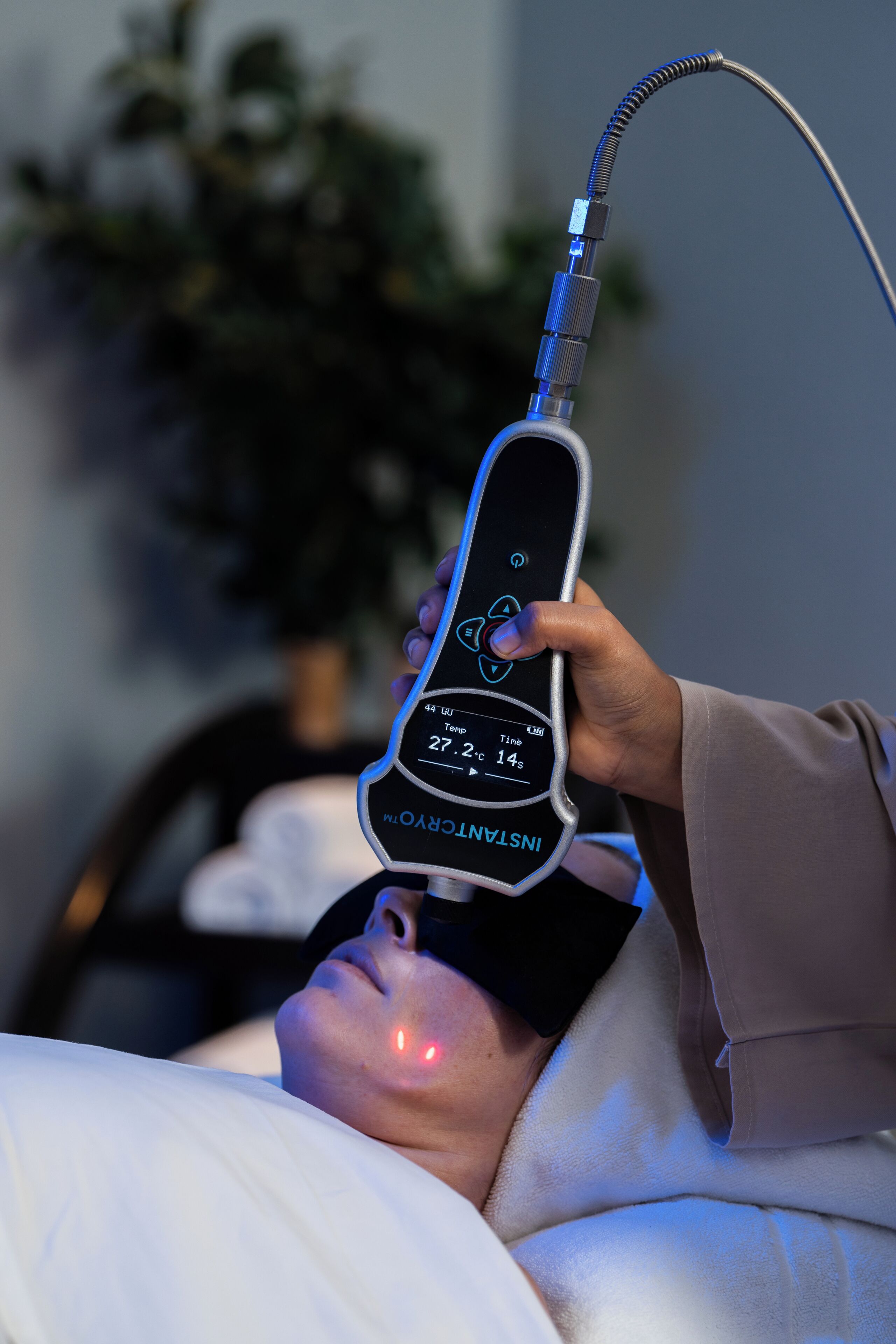 A person lying in bed with a medical device emitting red light.